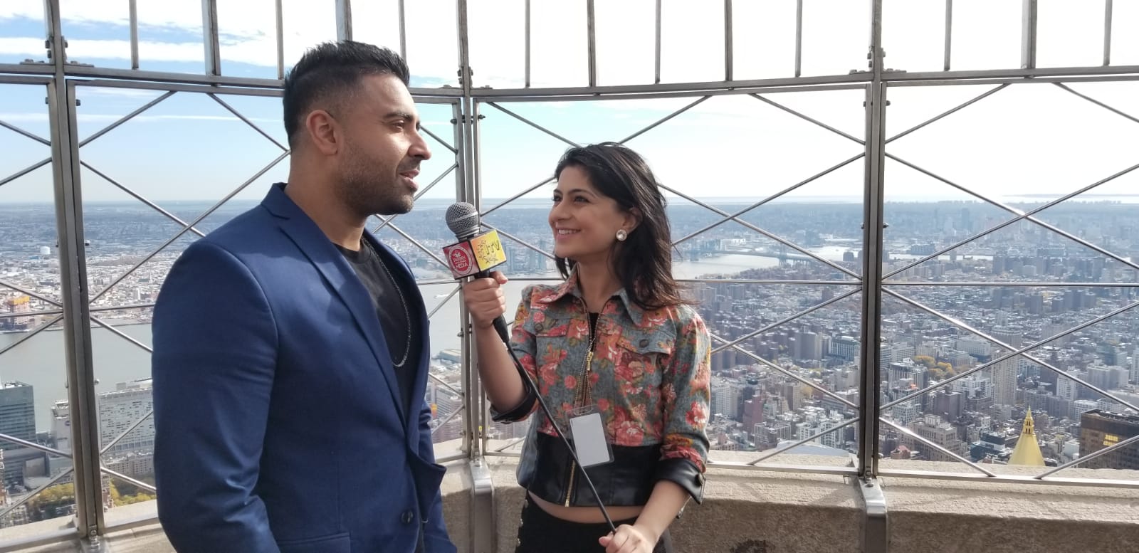 Aditi interviewing recording artist Jay Sean on a city observation deck.
